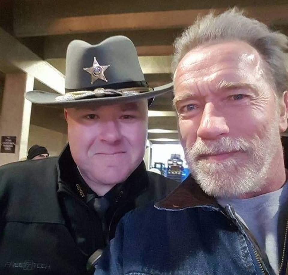 Jason Ratcliff in uniform posing with Arnold Schwarzenegger
